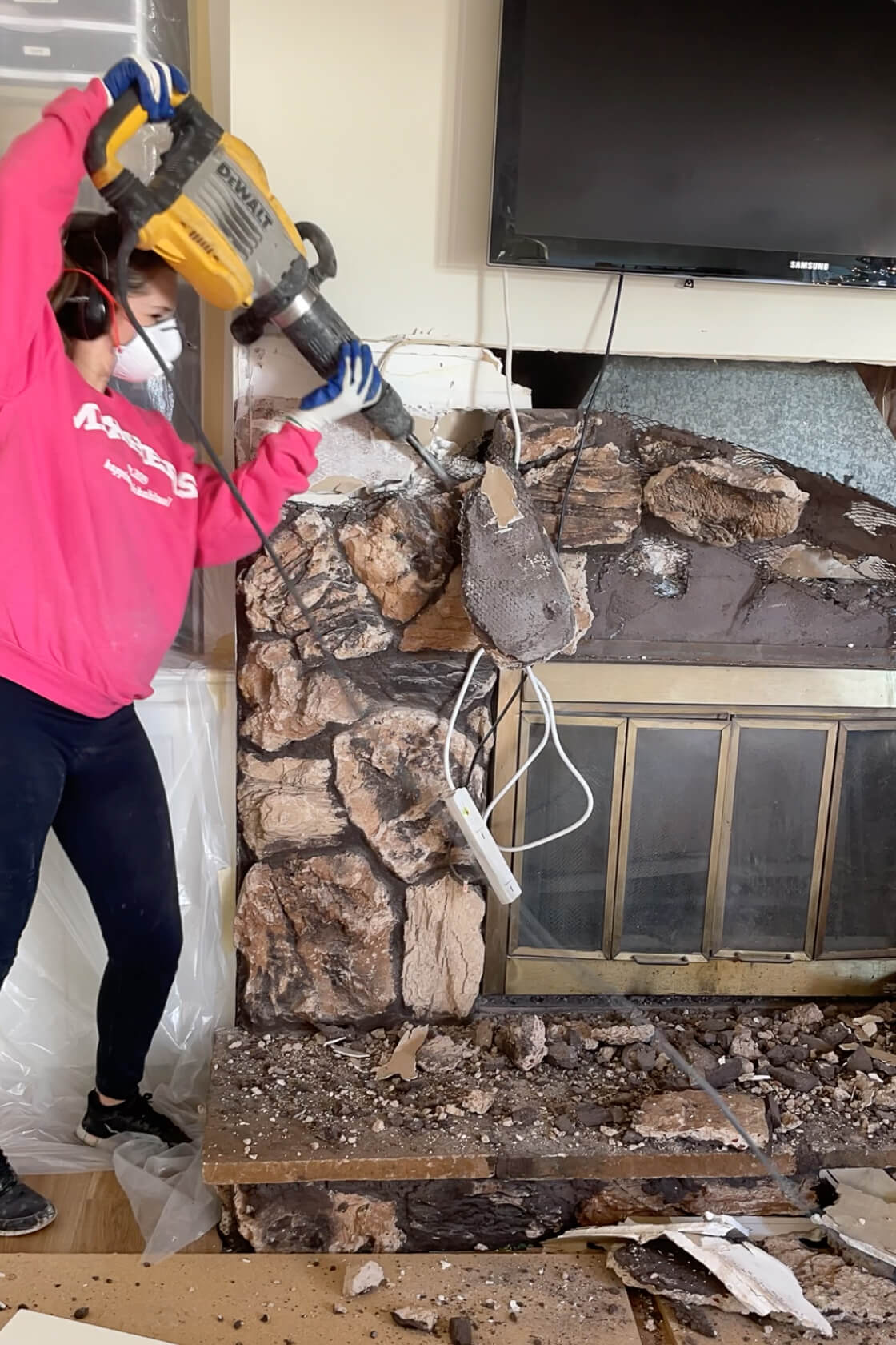 Using a demolition hammer to tear rock off of an ugly fireplace.